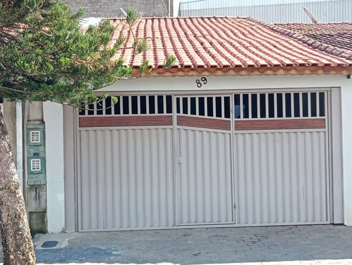Fachada da casa, com portão de garagem e muro branco