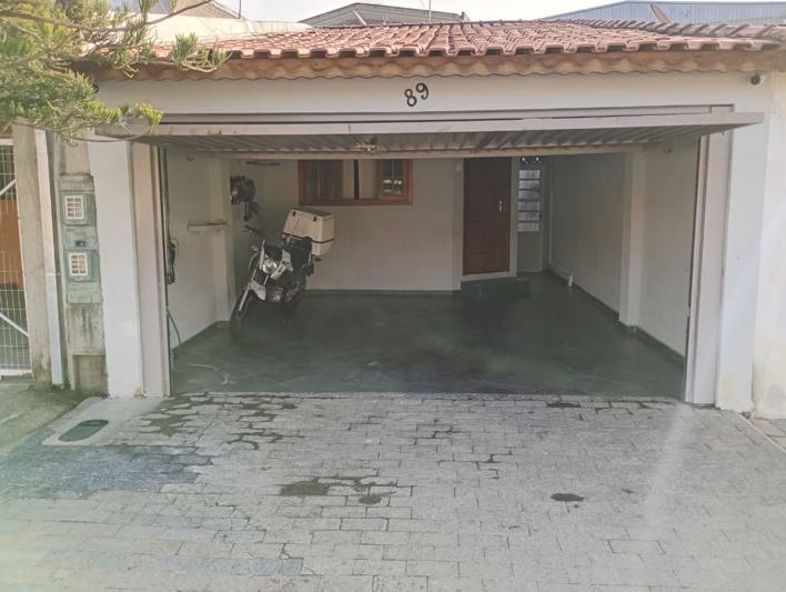 Garagem coberta vista de fora, com acesso à entrada da casa