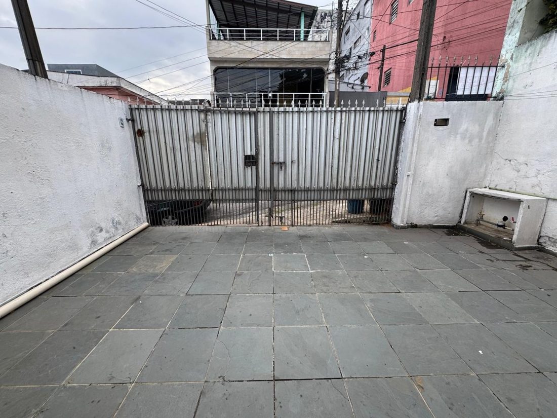 Quintal com piso de pedra e portão de ferro