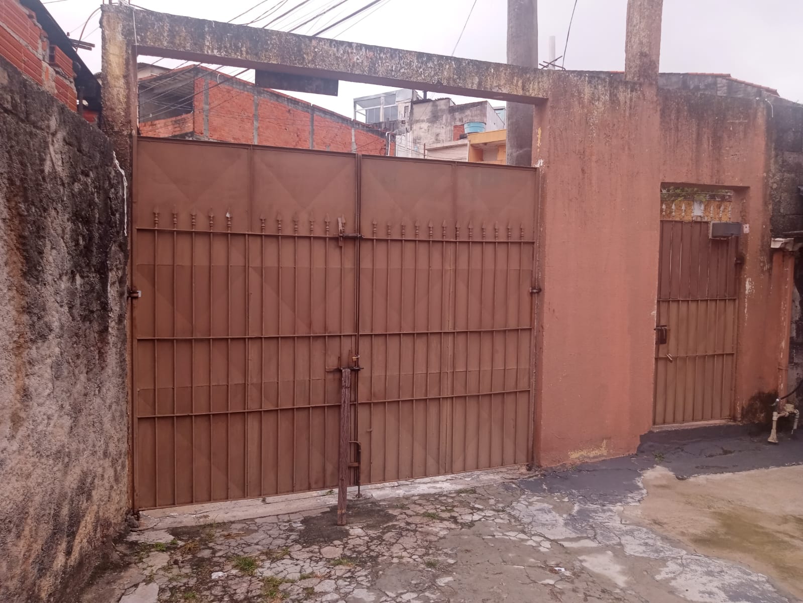 Fachada da casa, com portão e porta de ferro e paredes terracota