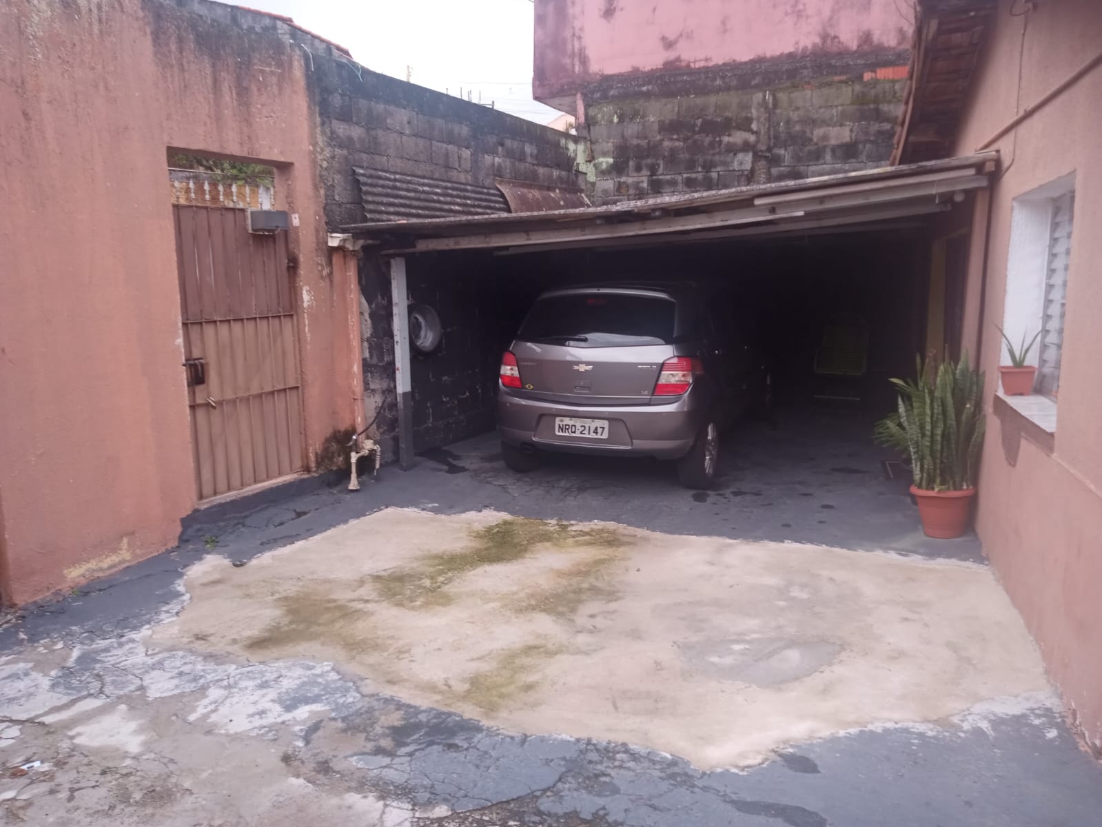 Estacionamento com paredes rosa, carro na garagem e planta em vaso