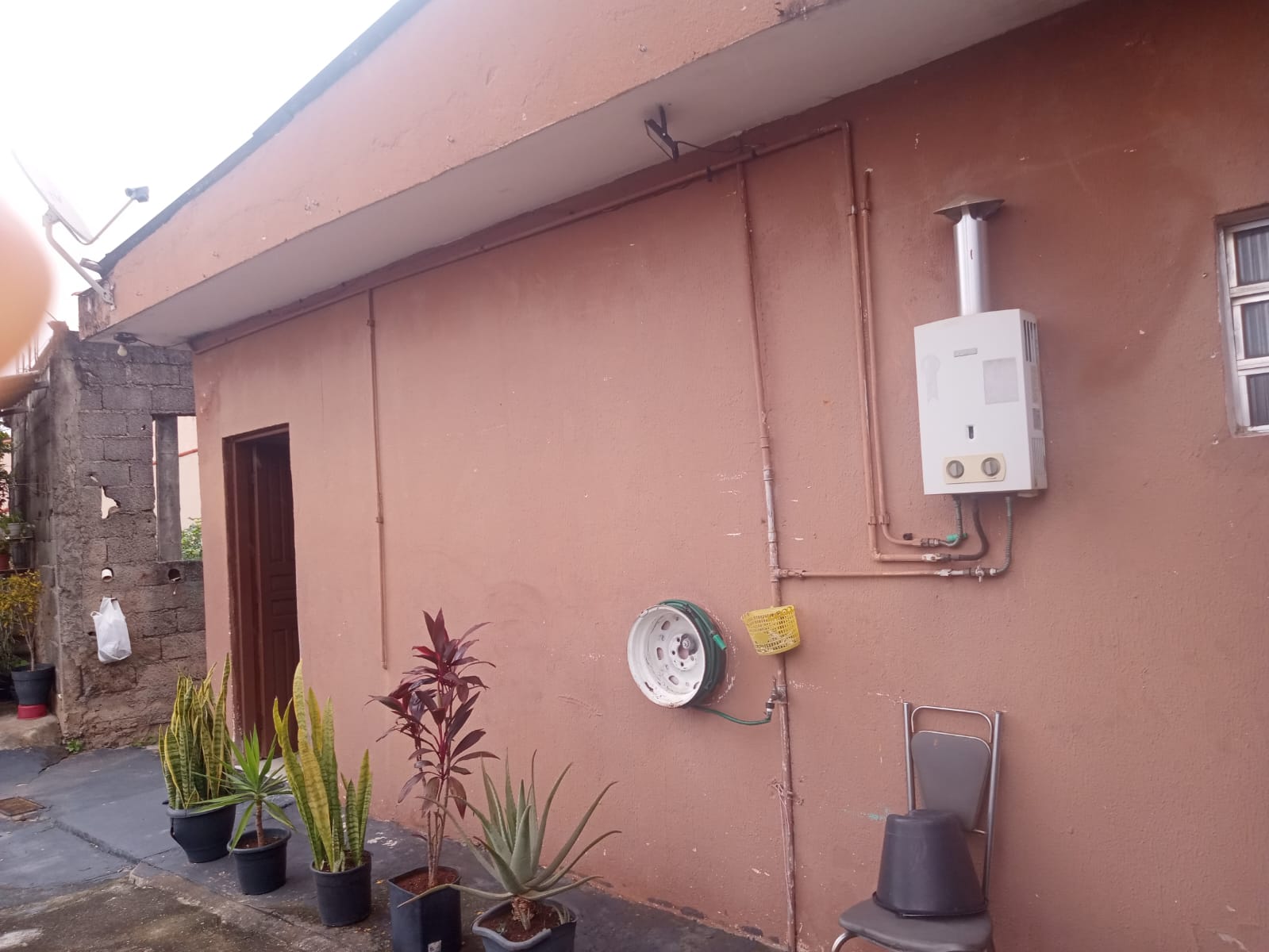 Área externa da casa, com plantas em vasos e aquecedor a gás