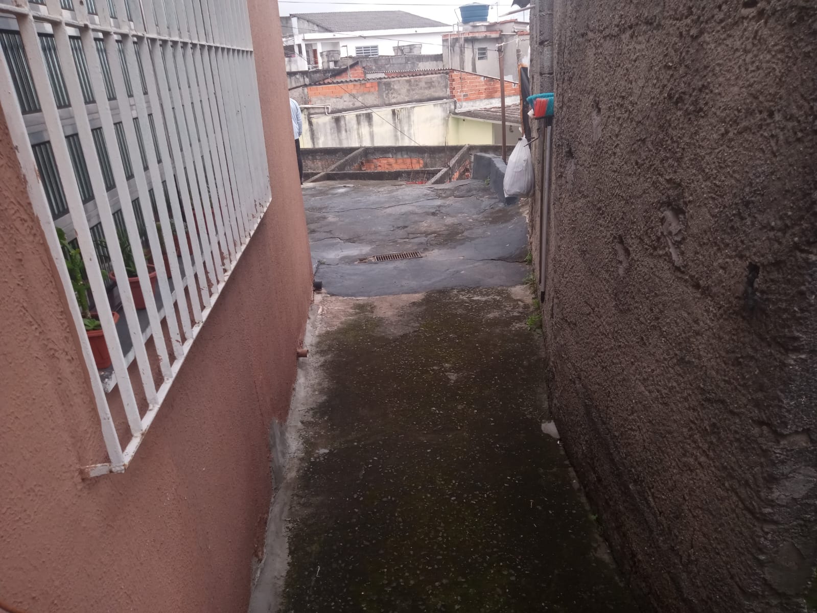 Passagem entre a casa e o muro, com janela gradeada