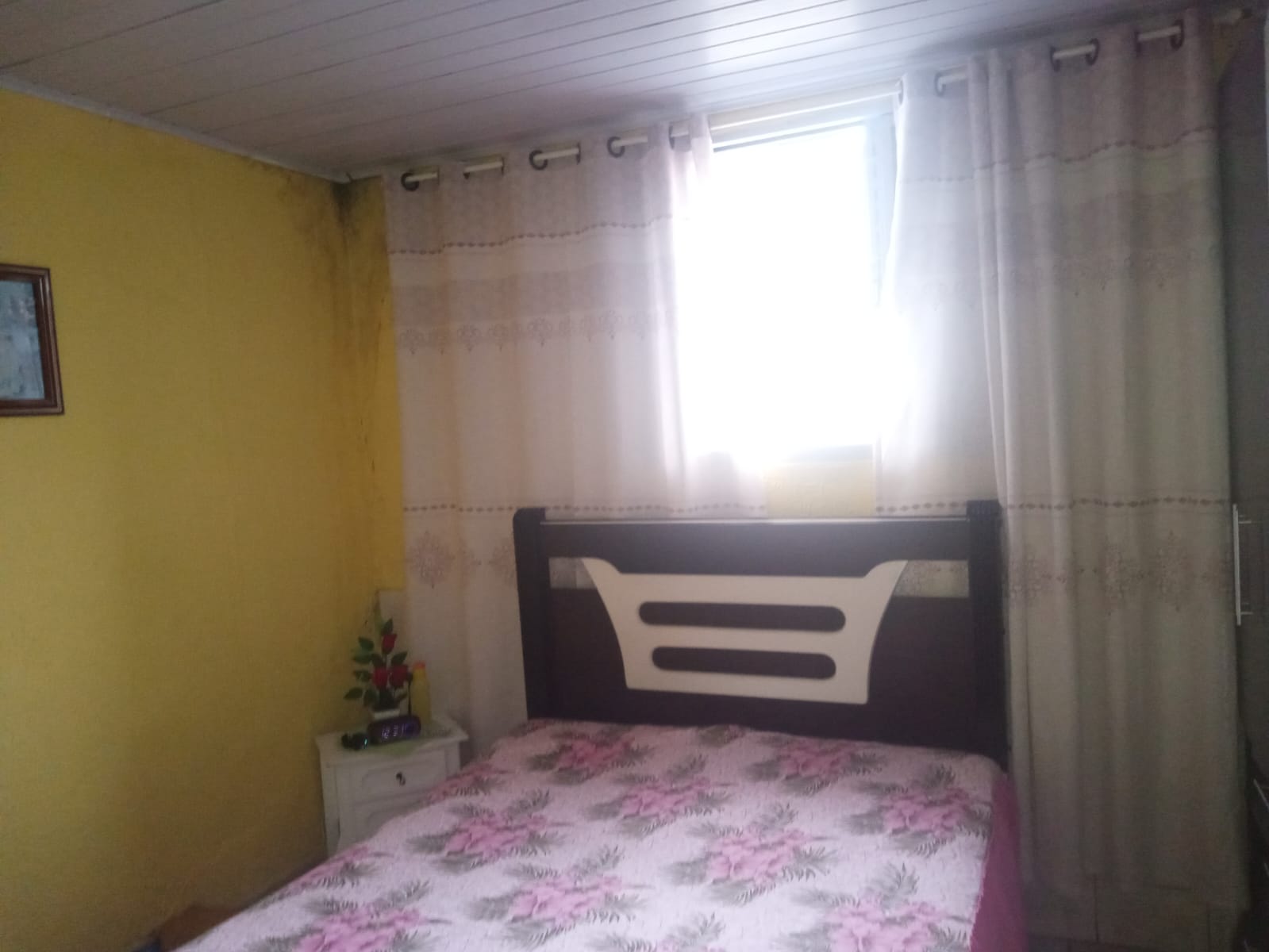 Dormitório com cama, cortinas e paredes amarelas