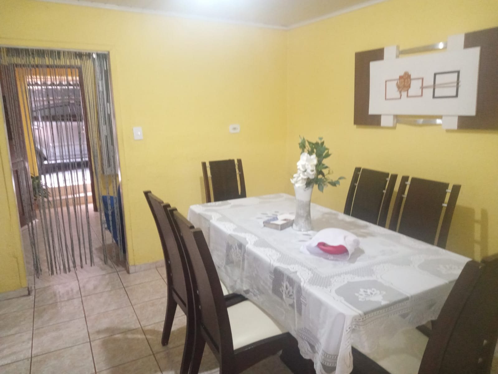 Sala de jantar com mesa de madeira e paredes amarelas