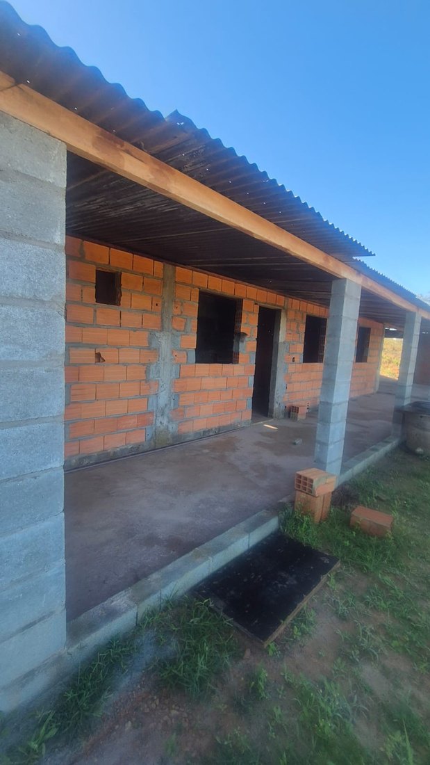 Fachada em obra, com varanda coberta ao longo de toda a frente
