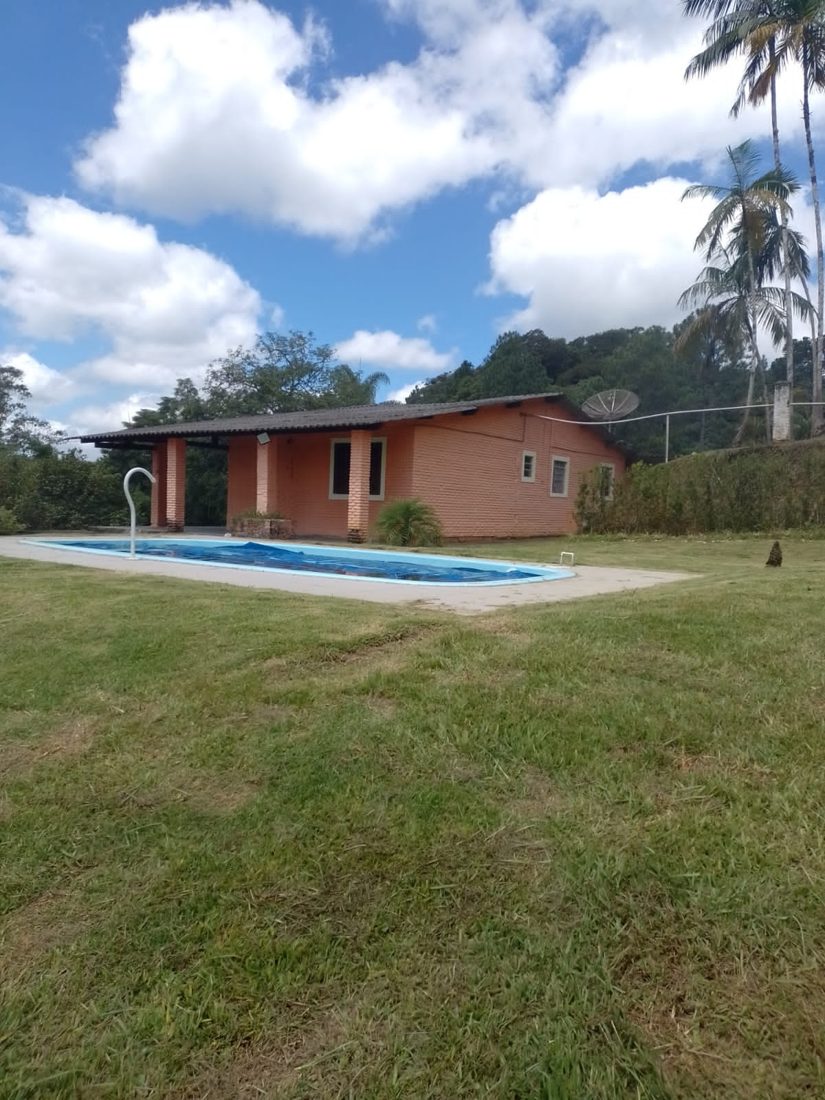 Casa da chácara vista do gramado, com a piscina na frente
